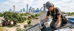 Professional roofer installing asphalt shingles on a steep roof with safety harness for new roof cost estimation.
