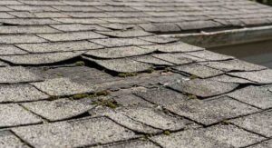 Professional roofer installing asphalt shingles on a steep roof with safety harness for new roof cost estimation.